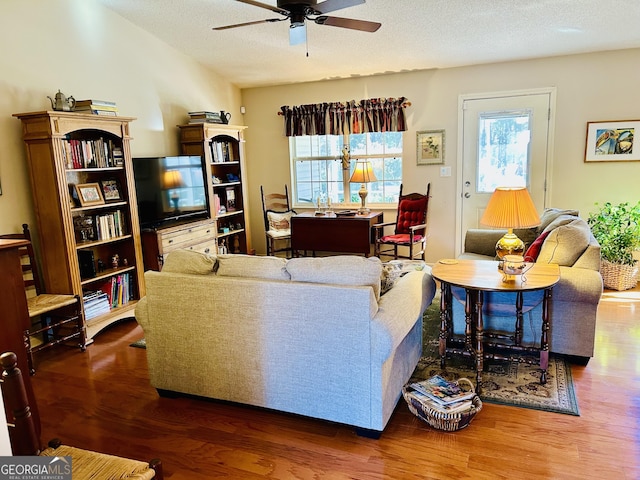 living room with a textured ceiling, ceiling fan, and hardwood / wood-style flooring