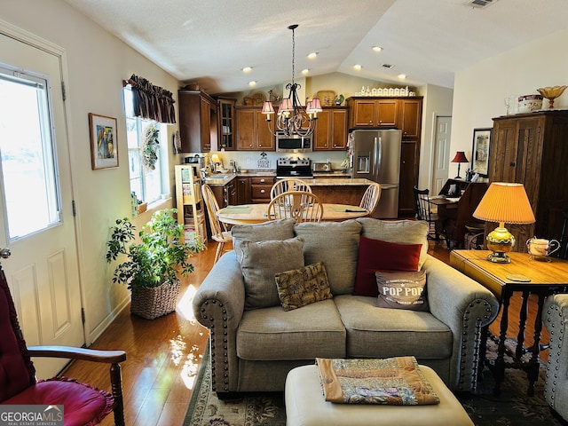 living room with dark hardwood / wood-style floors, lofted ceiling, and an inviting chandelier