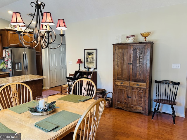 dining area with light wood-type flooring and an inviting chandelier