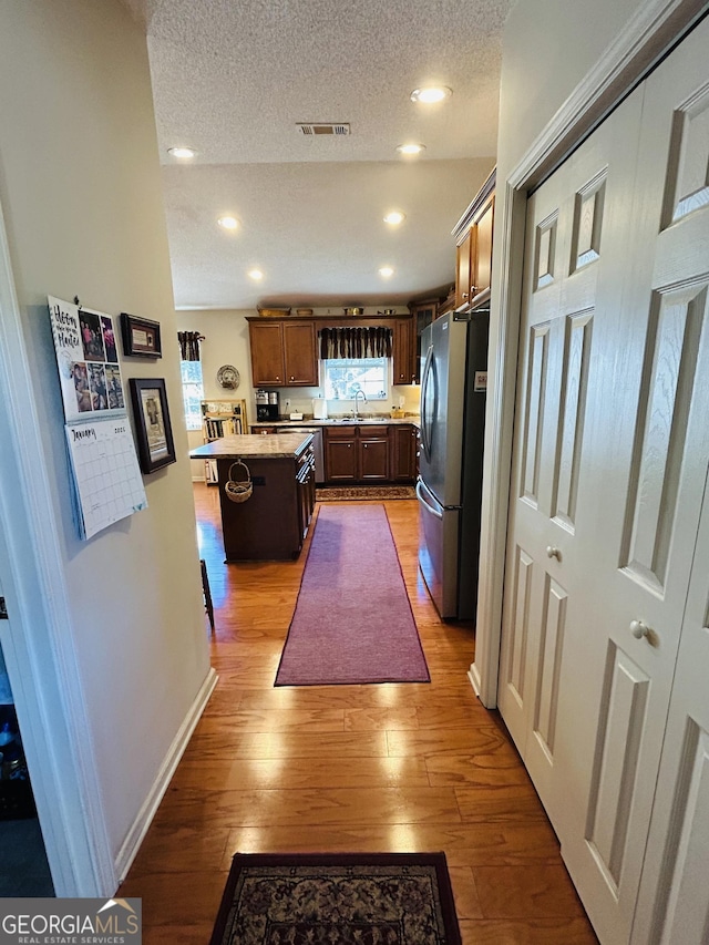 kitchen with a center island, sink, stainless steel refrigerator, a kitchen breakfast bar, and a textured ceiling