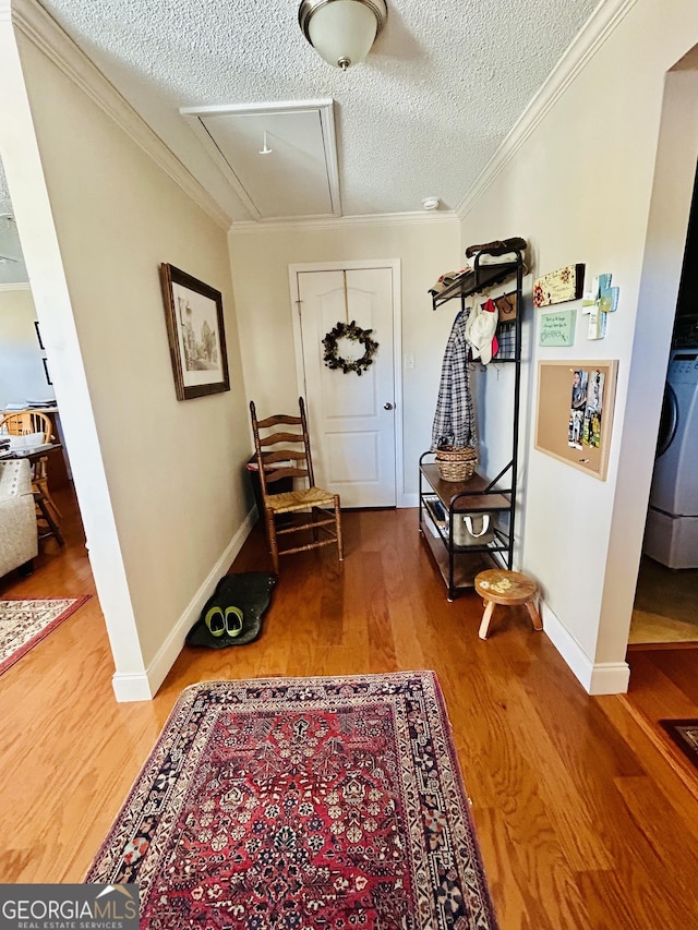 interior space with ornamental molding, washer / dryer, a textured ceiling, and hardwood / wood-style floors