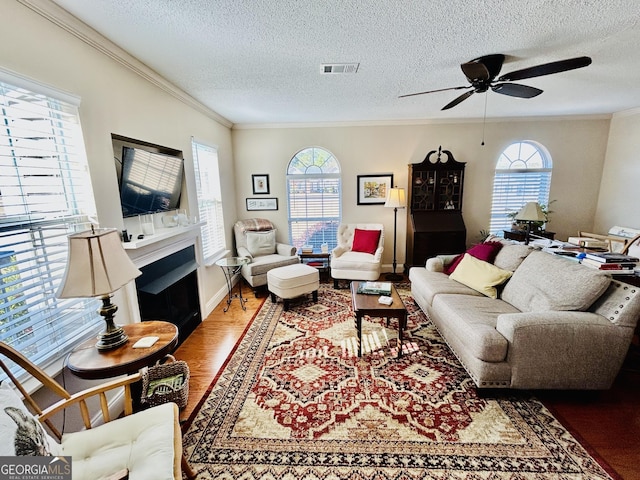 living room featuring wood-type flooring, crown molding, and a healthy amount of sunlight