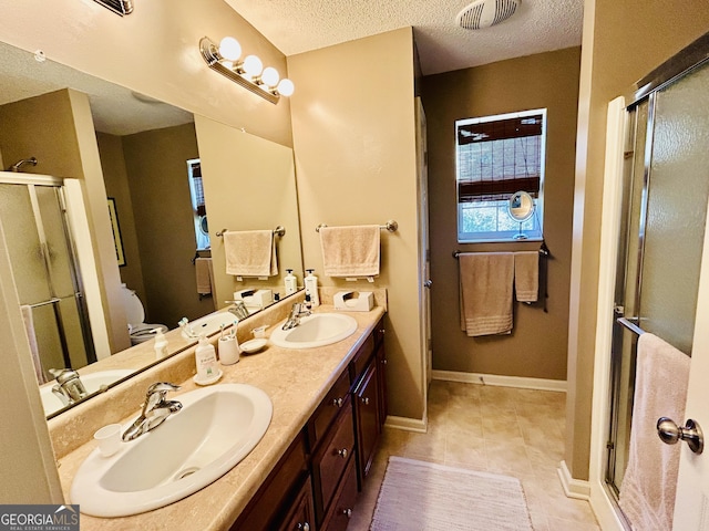 bathroom with a textured ceiling, tile patterned floors, walk in shower, and vanity