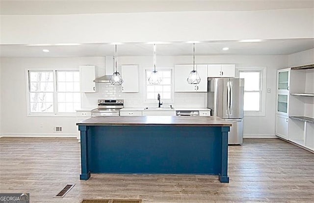 kitchen featuring hanging light fixtures, appliances with stainless steel finishes, white cabinetry, and a kitchen island