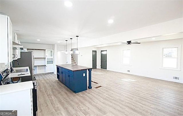 kitchen with a center island, white cabinetry, blue cabinetry, hanging light fixtures, and a breakfast bar area