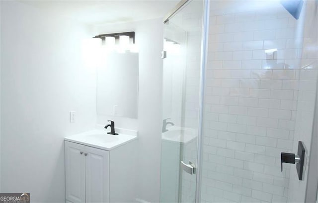 bathroom featuring a shower with shower door and vanity