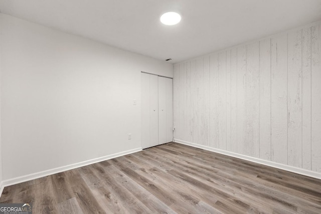 unfurnished room with hardwood / wood-style floors and wooden walls