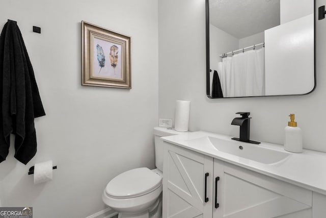 bathroom with a textured ceiling, toilet, and vanity