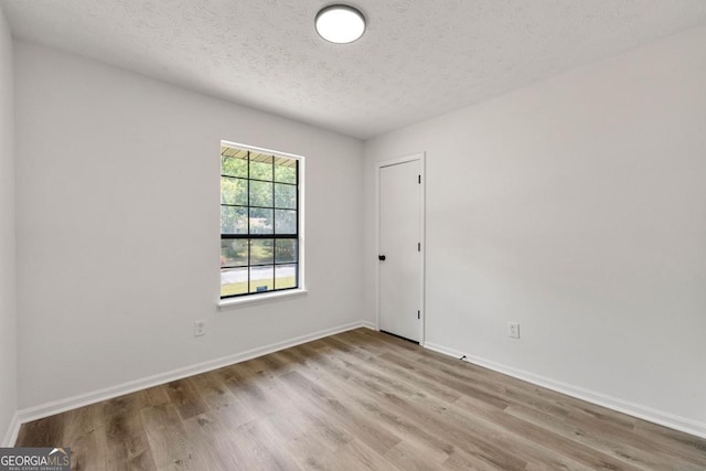 unfurnished room with a textured ceiling and light hardwood / wood-style flooring