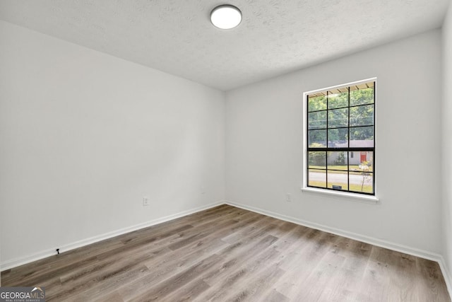 unfurnished room with wood-type flooring and a textured ceiling