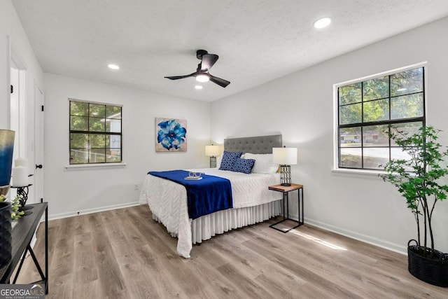 bedroom with ceiling fan, light hardwood / wood-style floors, and a textured ceiling