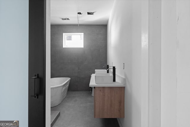 bathroom with vanity, a bathing tub, and concrete flooring