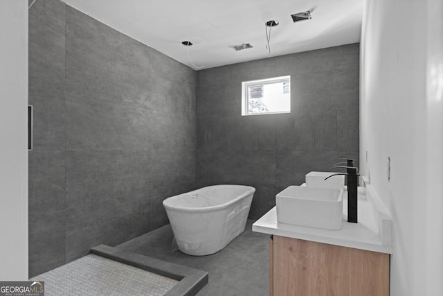 bathroom with a tub to relax in, vanity, and concrete floors