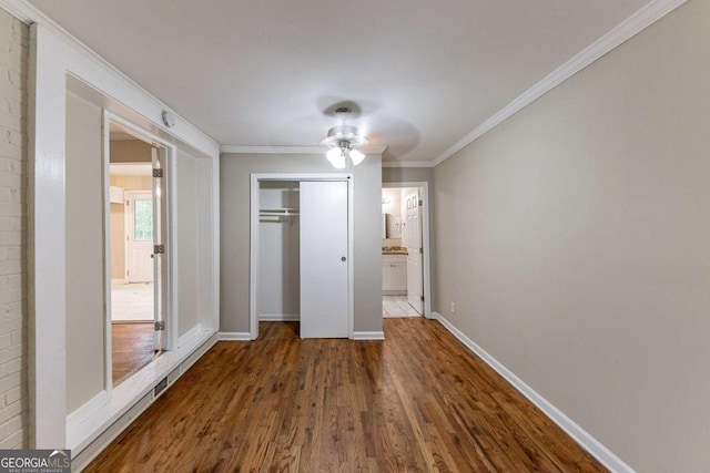 unfurnished bedroom with ceiling fan, a closet, hardwood / wood-style floors, and crown molding