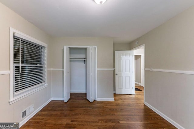 unfurnished bedroom with a closet and dark hardwood / wood-style flooring