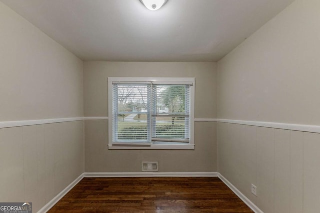 unfurnished room featuring dark wood-type flooring and wood walls