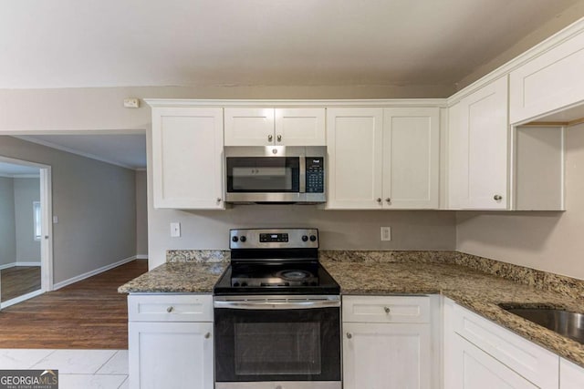 kitchen with white cabinets, appliances with stainless steel finishes, and dark stone countertops