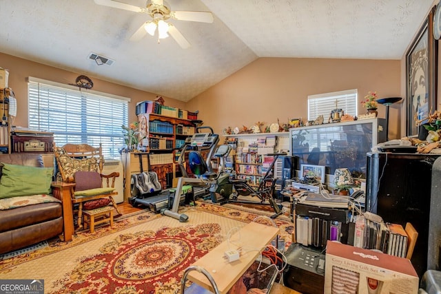 home office featuring lofted ceiling, ceiling fan, and a textured ceiling