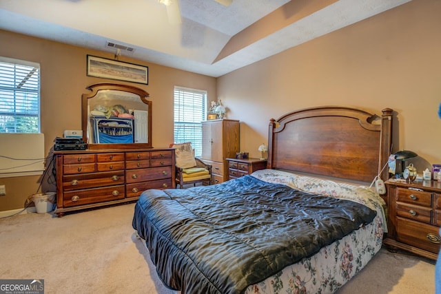 bedroom featuring light carpet, vaulted ceiling, a textured ceiling, and ceiling fan