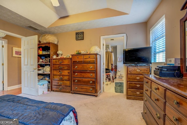 bedroom with ensuite bath, ceiling fan, vaulted ceiling, and light carpet