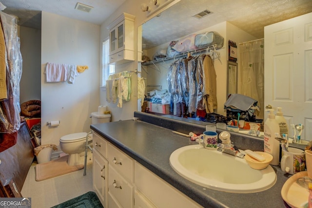 bathroom with toilet, a textured ceiling, vanity, and curtained shower