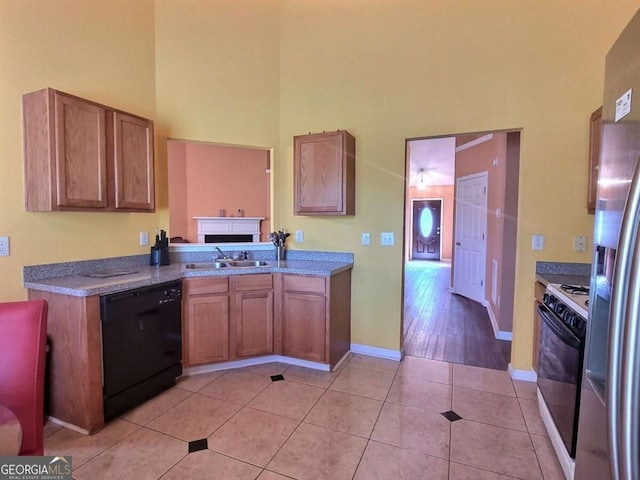 kitchen with gas stove, stainless steel refrigerator with ice dispenser, black dishwasher, sink, and light tile patterned floors