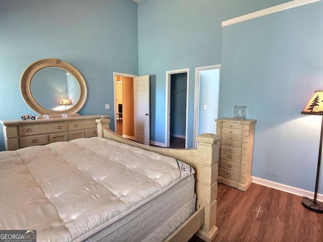 bedroom featuring a closet, a spacious closet, dark hardwood / wood-style flooring, and a high ceiling