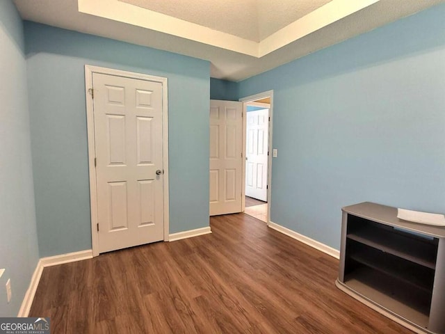 empty room with a raised ceiling and dark hardwood / wood-style floors