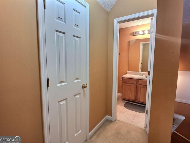 hall featuring lofted ceiling, light tile patterned floors, sink, and a textured ceiling