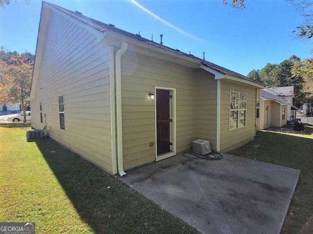 rear view of house with a lawn, central AC unit, and a patio