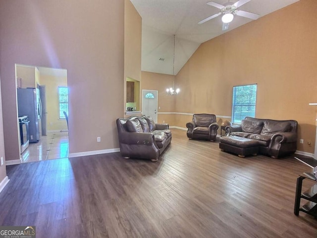 living room with hardwood / wood-style flooring, ceiling fan with notable chandelier, high vaulted ceiling, and a healthy amount of sunlight