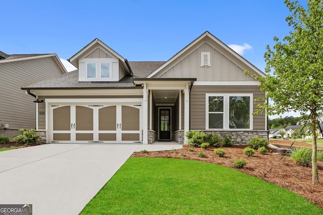 craftsman-style house with a shingled roof, stone siding, driveway, and an attached garage
