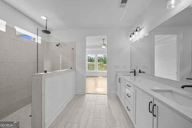 bathroom with a walk in shower, double vanity, a ceiling fan, and baseboards