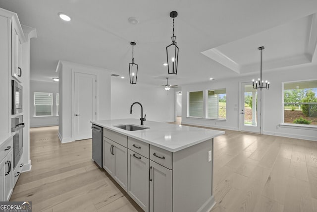 kitchen with a sink, stainless steel appliances, a ceiling fan, light countertops, and light wood-style flooring