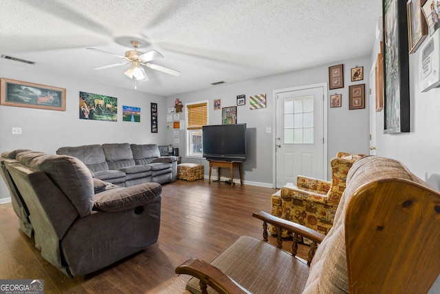 living room featuring a textured ceiling, ceiling fan, and dark wood-type flooring