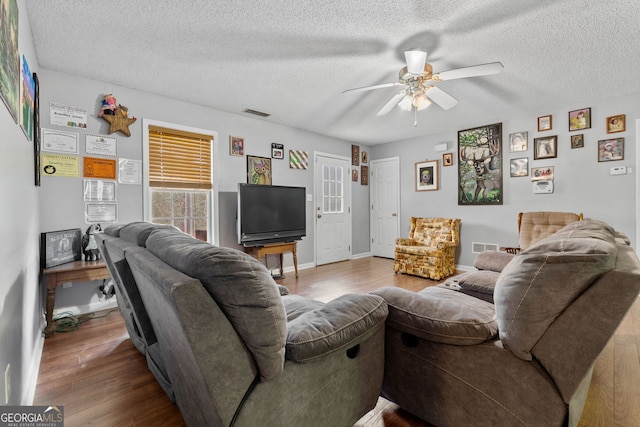 living room with a textured ceiling, ceiling fan, and hardwood / wood-style flooring