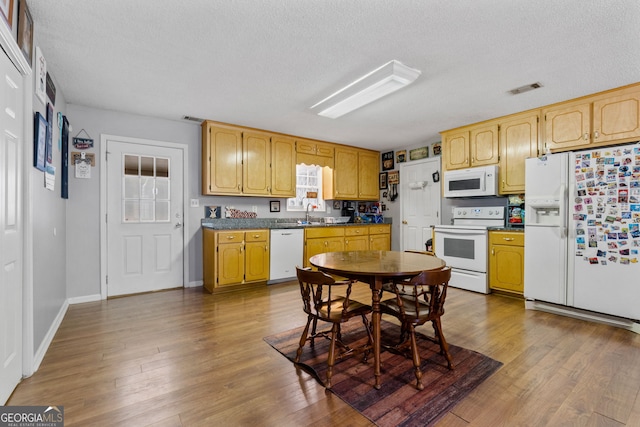 kitchen featuring sink, white appliances, a textured ceiling, and hardwood / wood-style floors