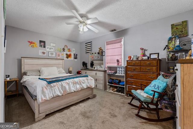 carpeted bedroom with ceiling fan and a textured ceiling