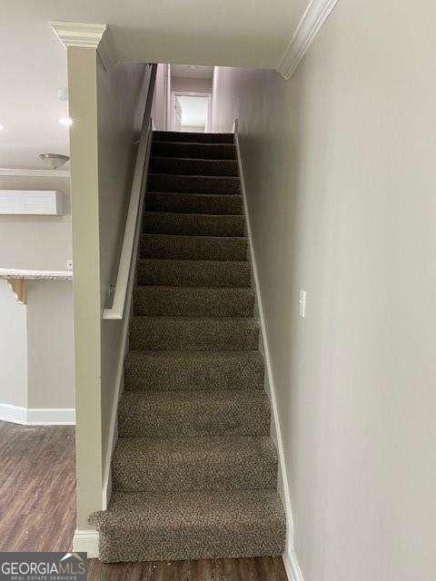 stairs featuring ornamental molding and hardwood / wood-style floors