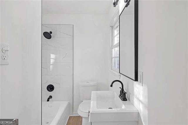 full bathroom featuring toilet, tiled shower / bath, hardwood / wood-style flooring, and sink