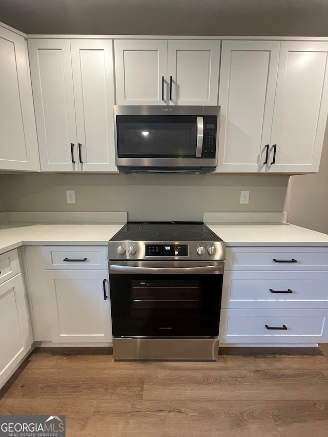 kitchen with light wood-type flooring, stainless steel appliances, and white cabinetry