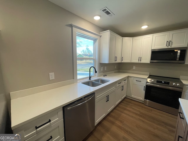 kitchen with dark wood-type flooring, stainless steel appliances, white cabinetry, and sink