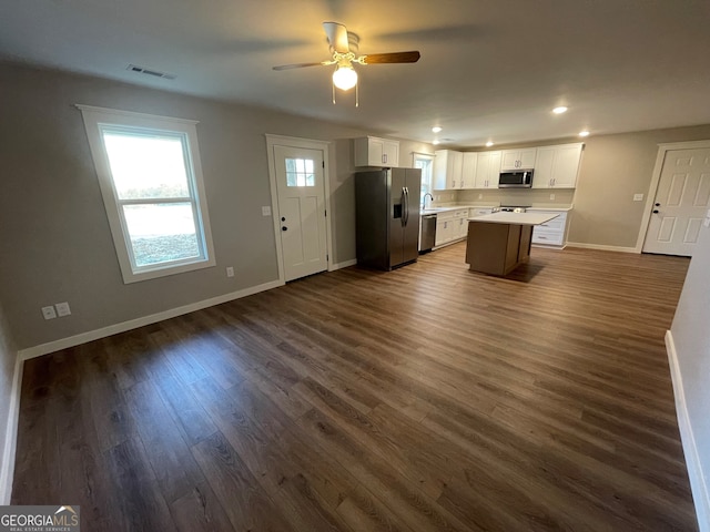 kitchen featuring ceiling fan, a center island, dark wood-type flooring, appliances with stainless steel finishes, and white cabinets