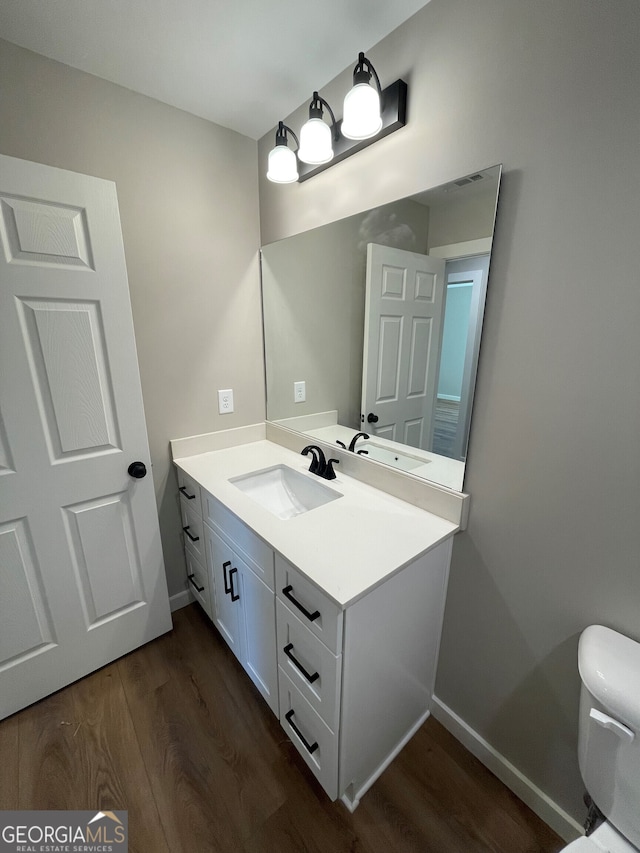 bathroom featuring toilet, vanity, and hardwood / wood-style flooring