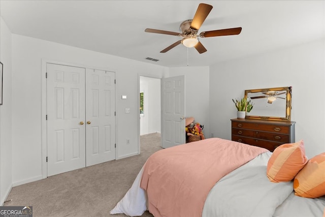 bedroom with ceiling fan, light colored carpet, and a closet