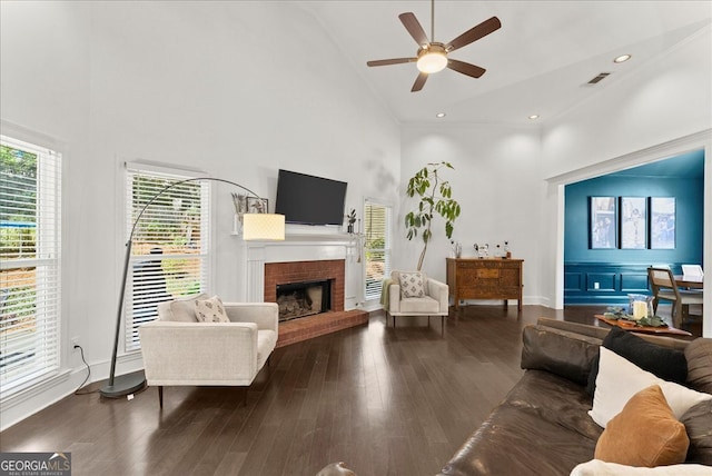 living room with ceiling fan, a fireplace, dark hardwood / wood-style floors, and high vaulted ceiling