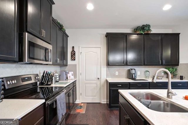 kitchen featuring tasteful backsplash, sink, dark hardwood / wood-style flooring, stainless steel appliances, and light stone countertops