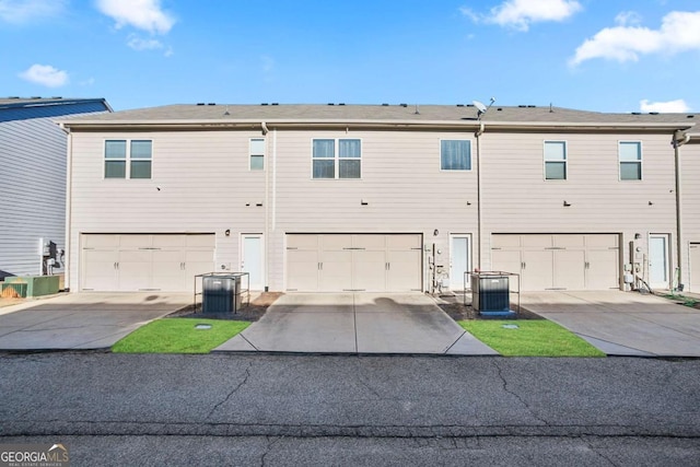 back of property featuring central AC unit and a garage