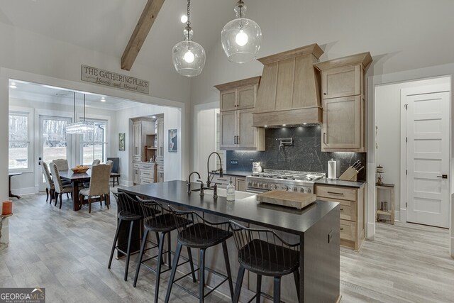 4621 Stanley Rd, Flowery Branch, GA 30542 - kitchen featuring premium range hood, dark countertops, light wood-style flooring, tasteful backsplash, and stainless steel range with gas stovetop