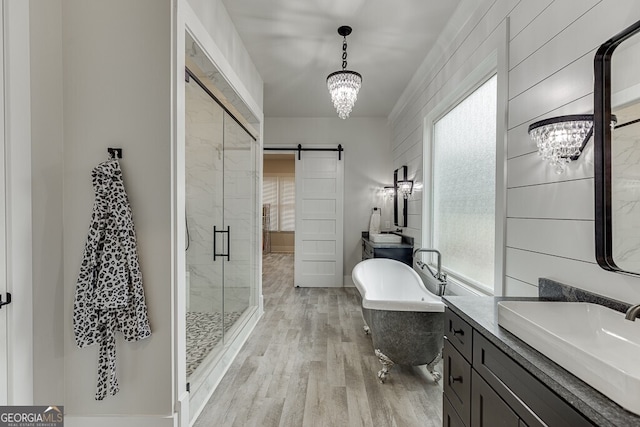 4621 Stanley Rd, Flowery Branch, GA 30542 - bathroom featuring a chandelier, wood finished floors, a shower stall, and healthy amount of natural light